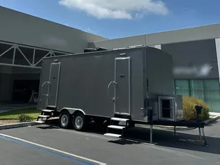 A large restroom trailer parked outside a commercial building
