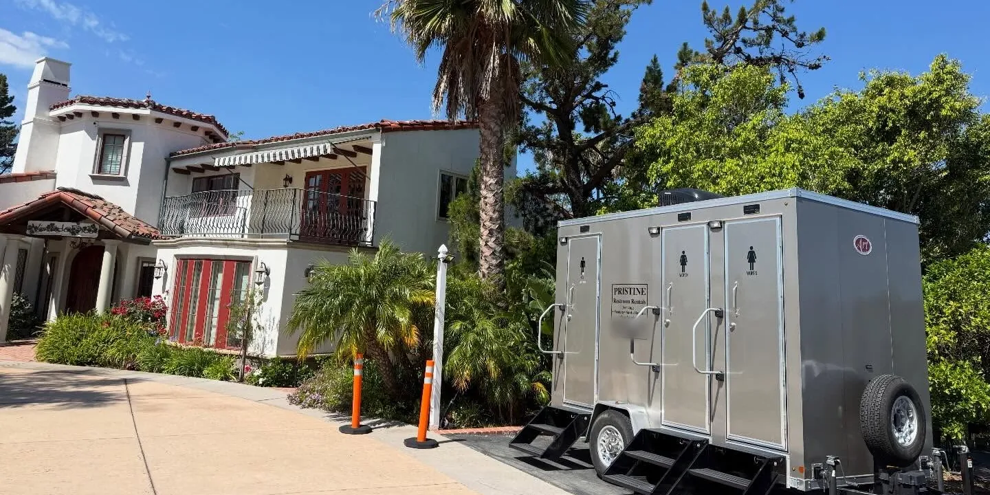 A Pristine Restroom Rentals trailer set up at a wedding venue with palm trees